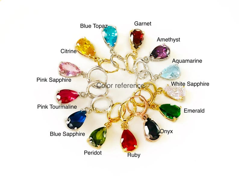 Op de afbeelding: Een verzameling edelsteen oorbellen in verschillende kleuren, waaronder blauwe topaas, citrien, granaat, amethist, aquamarijn, roze saffier, witte saffier, roze toermalijn, blauwe saffier, peridot, robijn, onyx en smaragd. Met een "color reference" label.