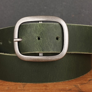 May include: A dark green leather belt with a silver buckle. The buckle is rectangular with rounded corners.