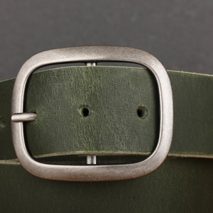 May include: A green leather belt with a silver buckle. The buckle is a simple, rectangular design with rounded edges.