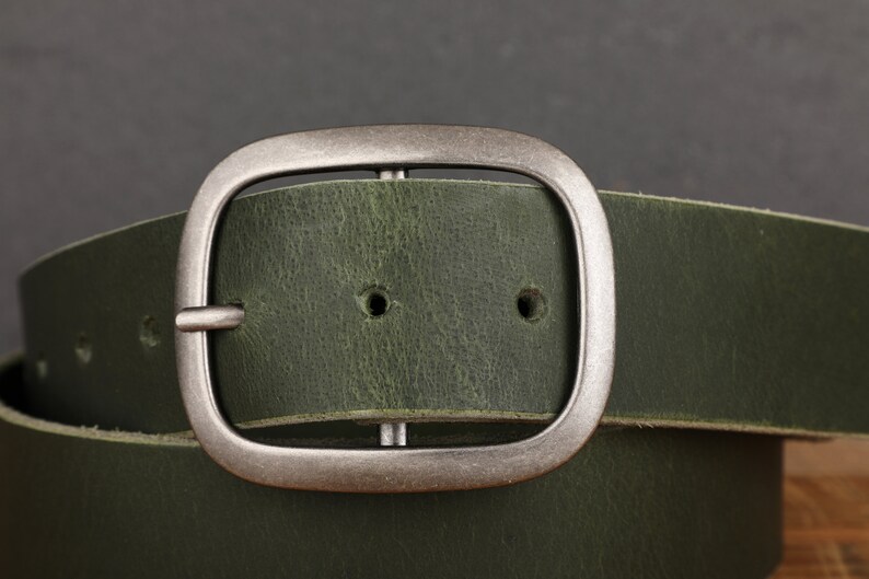 May include: A green leather belt with a silver buckle. The buckle is a simple, rectangular design with rounded edges.