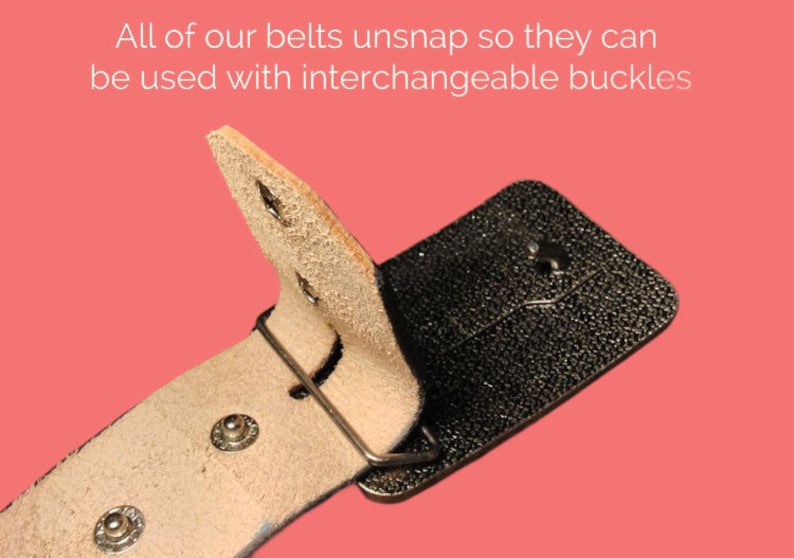 May include: A close-up of a brown leather belt with a black metal buckle. The belt is designed to be interchangeable with other buckles.