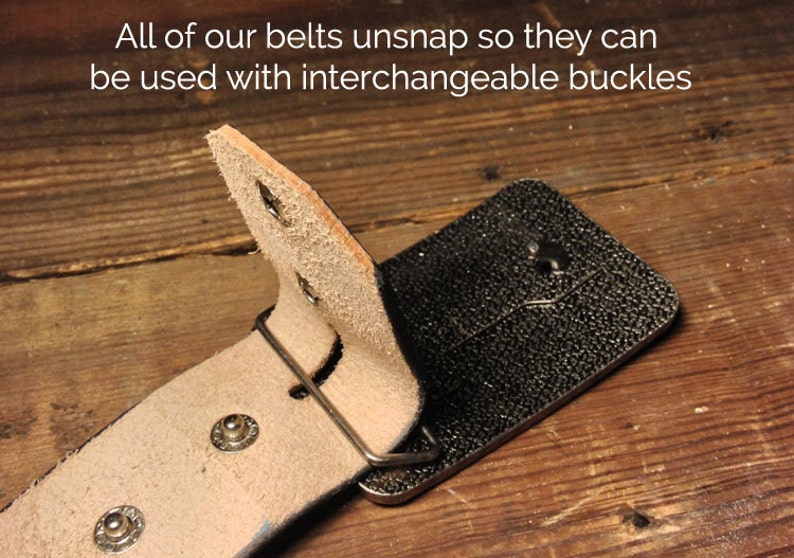 May include: A brown leather belt with a silver buckle. The belt is designed to be interchangeable with other buckles. The text "All of our belts unsnap so they can be used with interchangeable buckles" is visible in the image.