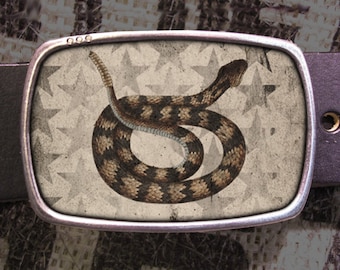 Peut inclure: Une boucle de ceinture argentée avec un motif de serpent brun et noir sur fond blanc avec un motif d'étoiles.
