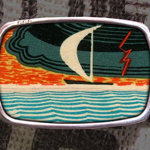 Fibbia per cintura con stampa a blocchi in stile vintage, raffigurante una barca a vela con fulmini sull'oceano