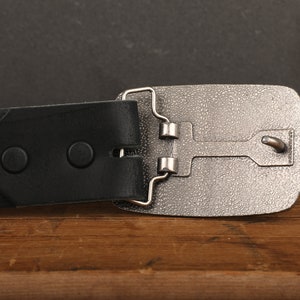 a black belt with a silver buckle on a wooden table