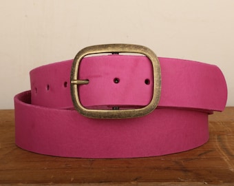 Puede incluir: Un cinturón de cuero rosa con una hebilla ovalada dorada.