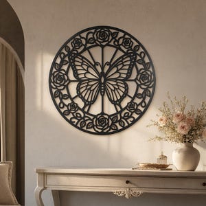 Peut inclure: Une décoration murale circulaire noire présentant une silhouette de papillon centrale entourée d'une bordure décorative de roses et de feuilles. Le design découpé complexe est symétrique, avec des lignes fines formant les ailes du papillon.