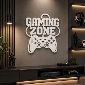 May include: White metal wall art featuring the text "GAMING ZONE" and a controller design. The artwork is mounted on a dark grey wall. The room has a modern aesthetic with black furniture and shelving.