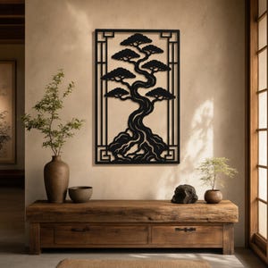 May include: A black metal wall art piece depicting a bonsai tree within a rectangular frame. The tree's branches and roots are intricately detailed. The artwork is mounted on a beige wall above a wooden console.