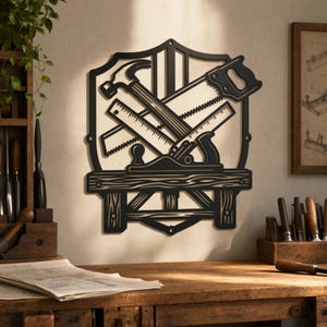 May include: A black metal wall art piece shaped like a shield, featuring a cutout design of a hammer, a hand saw, and a wood plane resting on a workbench. The silhouette is mounted on a wall, showcasing detailed tool outlines and wood grain textures.