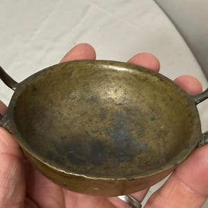 Puede incluir: Una taza de cer&aacute;mica blanca con un asa negra y el texto "But First, Coffee" en un estilo manuscrito. La taza est&aacute; sobre una superficie blanca. La taza mide aproximadamente 10 cm de alto.