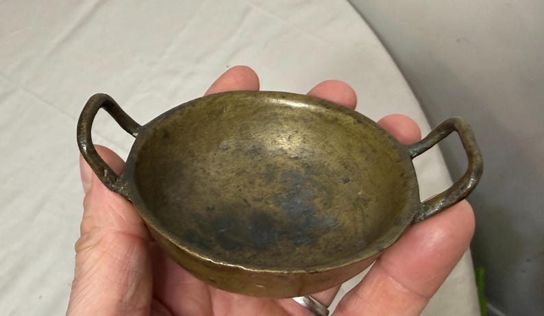 Puede incluir: Una taza de cer&aacute;mica blanca con un asa negra y el texto "But First, Coffee" en un estilo manuscrito. La taza est&aacute; sobre una superficie blanca. La taza mide aproximadamente 10 cm de alto.