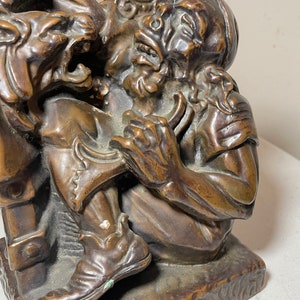 Puede incluir: Una escultura de bronce que representa a un hombre siendo atacado por una criatura monstruosa. El hombre lleva un turbante y una t&uacute;nica, y la criatura tiene dientes y garras afiladas. La escultura es detallada y realista, y es un gran ejemplo de la habilidad del artista.