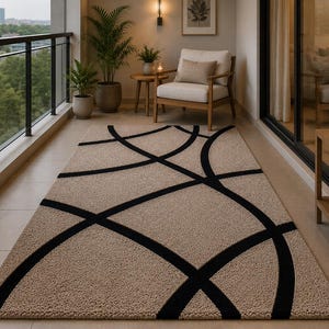 May include: A rectangular area rug featuring a textured beige surface with a bold, black geometric pattern of intersecting curved lines. The rug is laid flat, showcasing a high-pile construction that creates a distinct contrast between the dark lines.