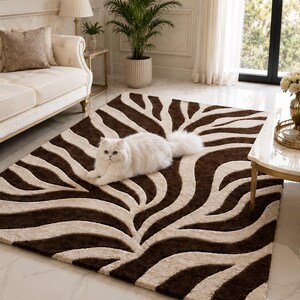 May include: A rectangular area rug featuring a high-contrast, dark brown and cream-colored zebra stripe pattern with a textured, tufted pile. A fluffy white cat is lying in the center of the rug, which is positioned on a light-colored floor.