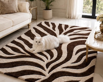 May include: A rectangular area rug featuring a high-contrast, dark brown and cream-coloured zebra stripe pattern with a textured, tufted pile. A fluffy white cat is lying in the centre of the rug, which is positioned on a light-coloured floor.