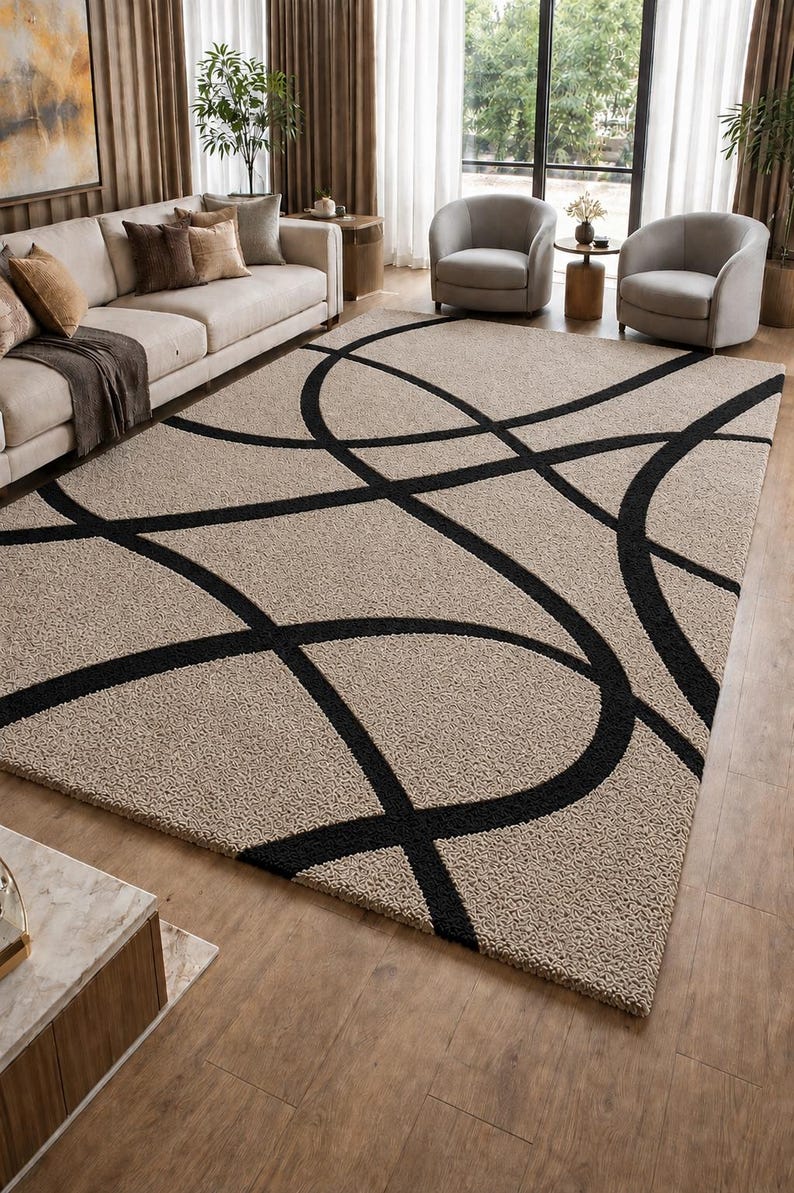 May include: A rectangular area rug featuring a textured beige pile with a bold, black geometric pattern of intersecting curved lines. The rug has a thick, shaggy surface texture and covers a large portion of the floor space in the room.