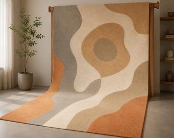 May include: A large area rug featuring an abstract pattern of flowing, organic shapes in shades of cream, beige, tan, grey, and burnt orange. The rug has a textured, tufted surface and is displayed draped over a wooden frame structure.