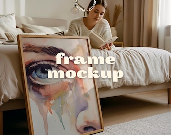 May include: A framed art print featuring a watercolor painting of a human eye with blue iris and colorful accents. The frame is made of light-colored wood. The words "frame mockup" are printed on the artwork.