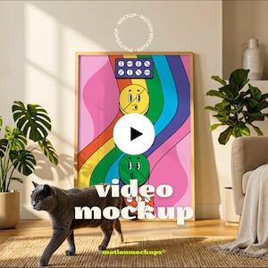 Puede incluir: Una impresión artística enmarcada con un diseño de dibujos animados colorido con gráficos de pastillas y caras sonrientes sobre un arcoíris. Las palabras "video mockup" se muestran en la imagen. Un gato gris camina sobre una alfombra.