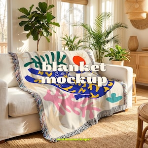 May include: A cream-colored blanket with a colorful abstract design featuring blue, pink, green, and yellow shapes, and an orange sun. The blanket is draped over a white sofa and has a fringe trim. The text "blanket mockup" is visible.