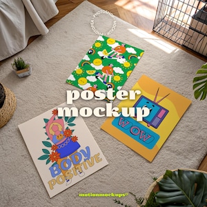 May include: Three colorful posters with unique designs are displayed on a neutral rug. One poster features a cartoon figure with the text "BODY POSITIVE". Another has a retro TV graphic with the word "WOW". The third poster has a green background with cartoon figures.