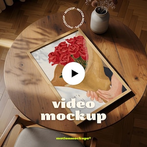 Peut inclure: Une impression d'art encadrée représentant un bouquet de roses rouges, présenté dans un emballage en papier brun clair. L'œuvre est posée sur une table en bois, avec les mots "video mockup" visibles. Un petit vase avec des fleurs séchées est également sur la table.