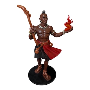 May include: A brown figurine of a muscular figure holding a staff and a flame. The figure wears a red and black skirt, a necklace, and armbands. The figurine stands on a black circular base.