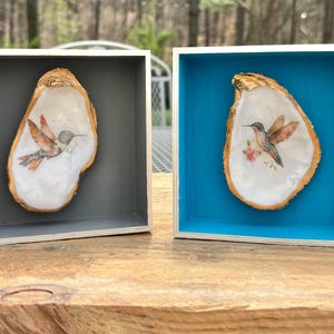 Può includere: Una tazza di ceramica bianca con manico nero e la scritta "But first, coffee" in nero, con un carattere a mano. La tazza è su una superficie bianca.