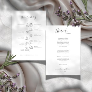 May include: Two white wedding stationery cards with black text. One card reads "itinerary" with a timeline of events. The other card says "thank you" with a message. Lavender sprigs and a satin cloth are in the background.