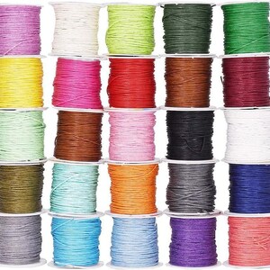 May include: A collection of colorful waxed cotton cord spools. The spools are arranged in rows, showcasing a variety of colors including pink, red, green, and blue. Each spool is tightly wound, offering a neat and organized display of craft supplies.