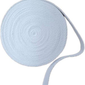 May include: A roll of light blue elastic ribbon. The ribbon is tightly wound into a circular shape, with a flat, smooth texture. A length of the ribbon extends from the roll, showing its flexible nature. Ideal for sewing and crafting projects.
