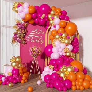 May include: A vibrant party scene with a pink backdrop and gold accents. The scene features a balloon arch in shades of pink, orange, and gold, with the words "Let's Party" in gold script. Floral arrangements and decorative elements complete the festive look.