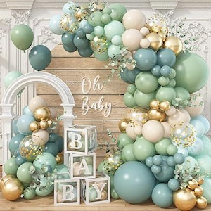 May include: A baby shower decoration featuring a balloon arch in shades of green, blue, and gold. The arrangement includes clear blocks spelling "BABY" and the words "Oh Baby" on a wooden backdrop. Additional balloons are scattered around the scene.