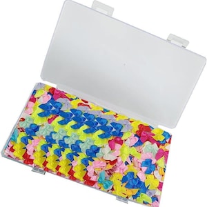 May include: A clear plastic container filled with colorful, miniature satin bows in shades of pink, blue, yellow, and green. The bows are neatly arranged inside the open container, creating a vibrant and organized display. Ideal for crafting and embellishments.