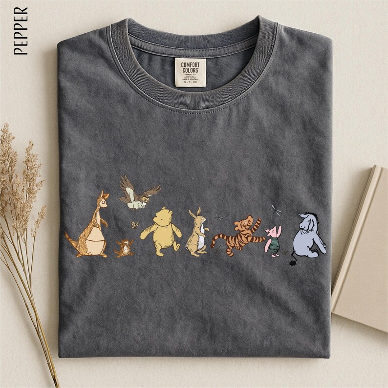 A gray t-shirt with a line of colorful cartoon animal characters printed on it, including a kangaroo, eagle, bear, lion, pig, and elephant.