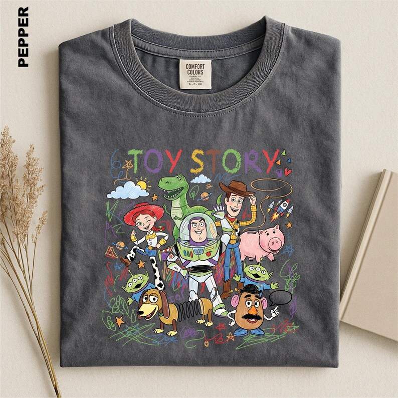 A gray t-shirt with a colorful graphic design featuring characters from the Toy Story movie, including Woody, Buzz Lightyear, and other beloved characters.