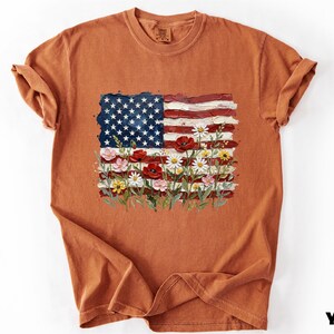 a brown t-shirt with a design of the American flag and flowers.