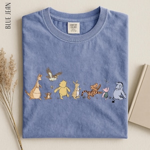 A blue t-shirt with a line of cartoon animal characters, including a kangaroo, eagle, bear, lion, and pig, arranged in a row.