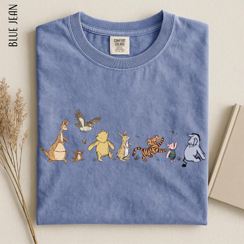 A blue t-shirt with a line of cartoon animal characters, including a kangaroo, eagle, bear, lion, and pig, arranged in a row.