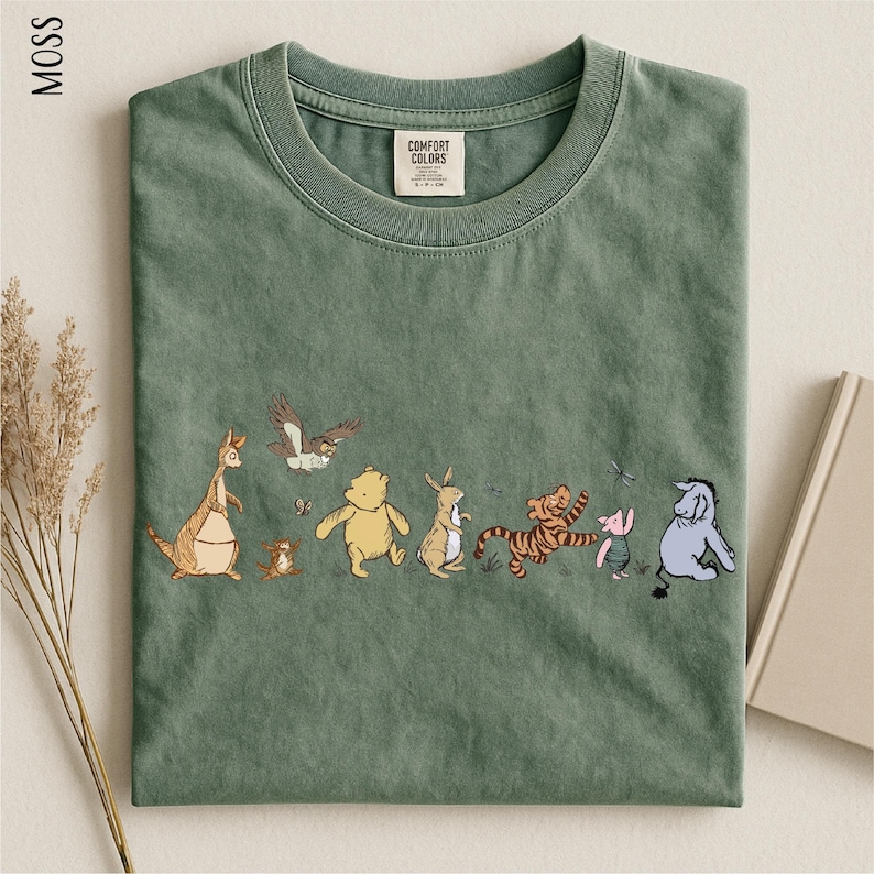 A green t-shirt with a line of cartoon animal characters printed on it, including a kangaroo, eagle, bear, lion, and other animals.