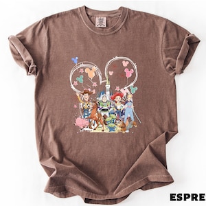 A brown t-shirt with a colorful graphic design featuring characters from the Toy Story movie, including Woody, Buzz Lightyear, and other beloved characters.