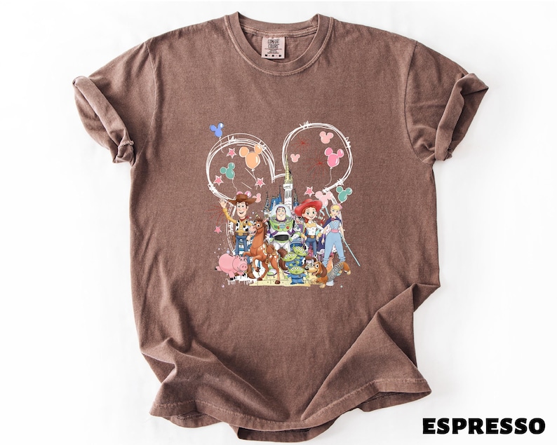 A brown t-shirt with a colorful graphic design featuring characters from the Toy Story movie, including Woody, Buzz Lightyear, and other beloved characters.