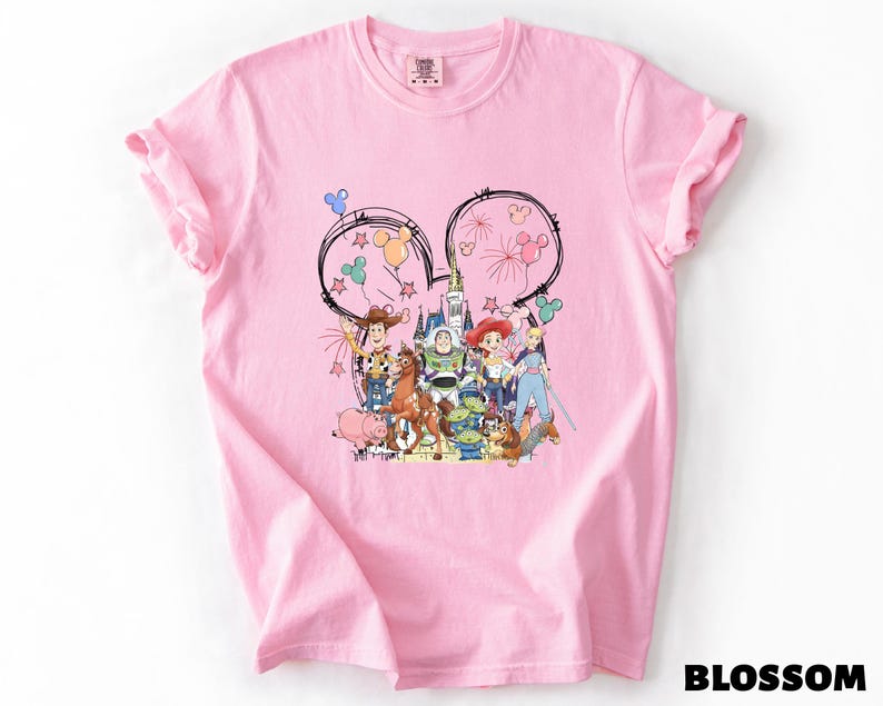 A pink t-shirt with a colorful graphic design featuring various cartoon characters and Disney-themed elements.