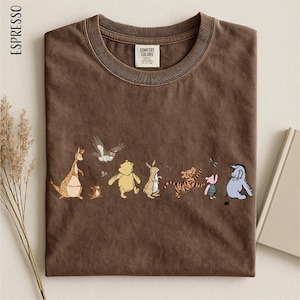 A brown t-shirt with a line of colorful cartoon animal characters printed on it, including a kangaroo, bear, tiger, pig, and elephant.