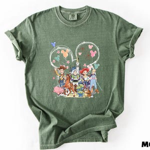 A green t-shirt with a colorful graphic design featuring characters from the Toy Story movie, including Woody, Buzz Lightyear, and other beloved characters.
