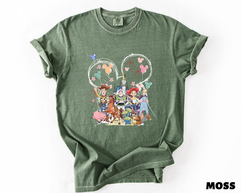 A green t-shirt with a colorful graphic design featuring characters from the Toy Story movie, including Woody, Buzz Lightyear, and other beloved characters.