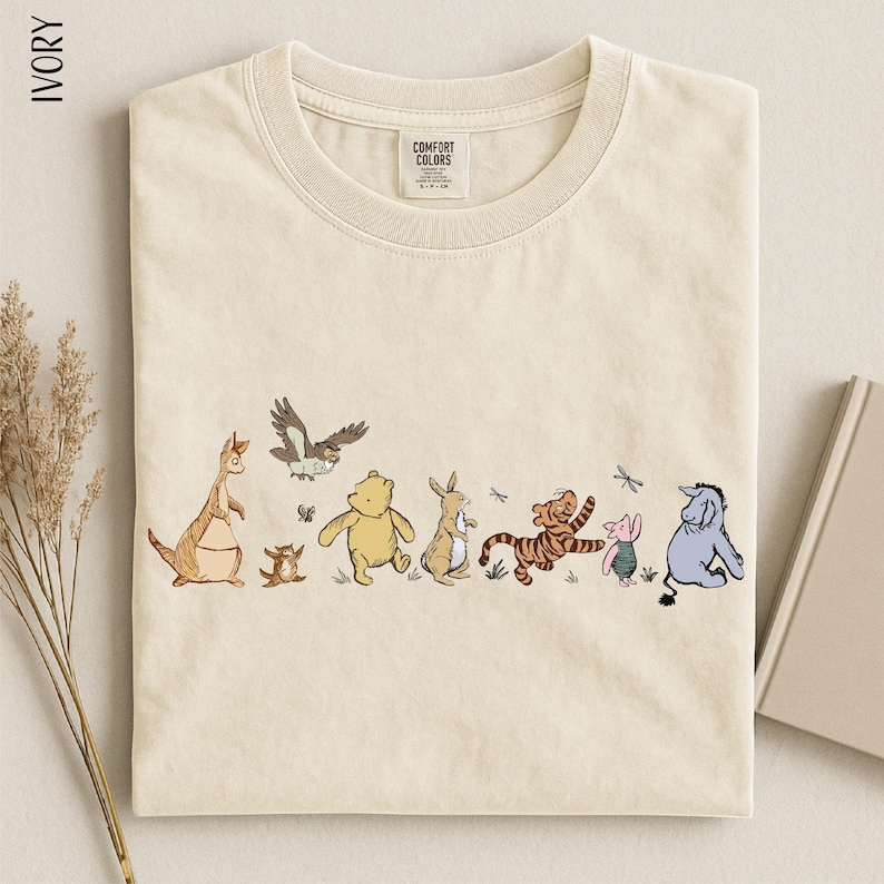 A t-shirt with a line of various Winnie the Pooh characters, including Tigger, Tigger's friend, and other beloved characters, printed on it.