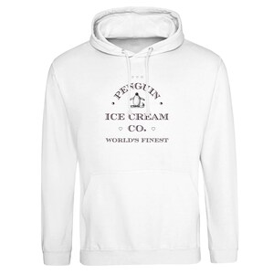 Op de afbeelding: Een witte hoodie met een zwarte afbeelding op de borst. Het ontwerp bevat een kleine illustratie van een pinguïn, de tekst PENGUIN ICE CREAM CO. en de woorden WORLD'S FINEST, geaccentueerd met kleine hartjes boven en onder de tekst.