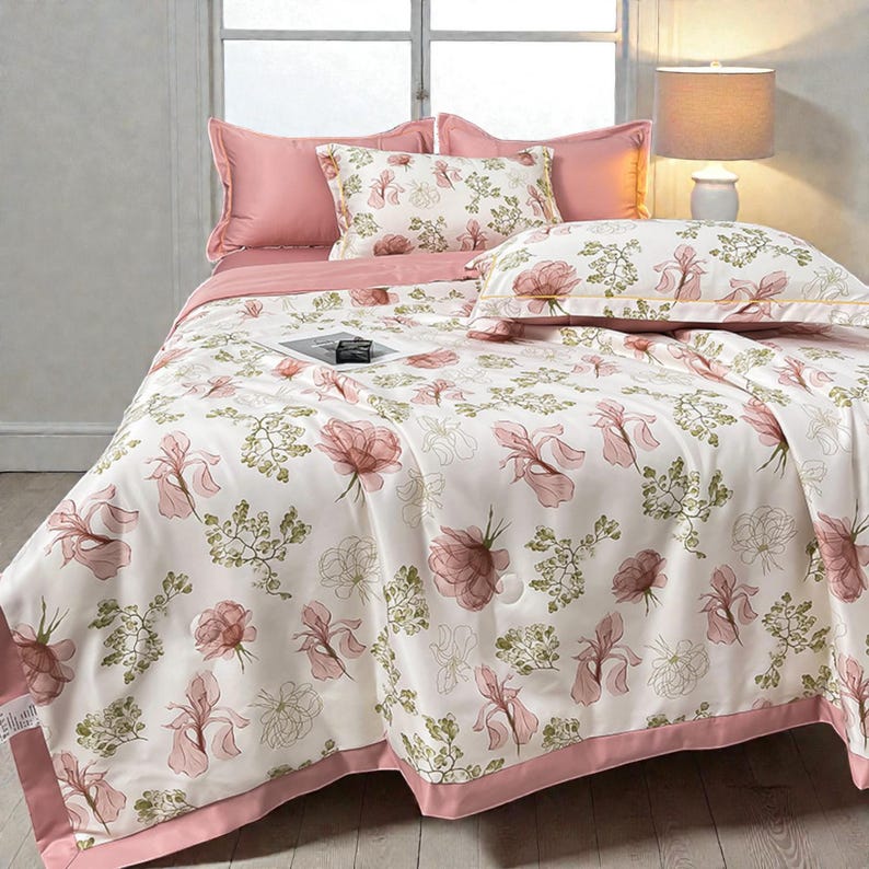 May include: A bed is made with a floral patterned comforter and pillow set. The bedding features a white background with pink and green floral designs. The set includes pink pillowcases and a pink border on the comforter.